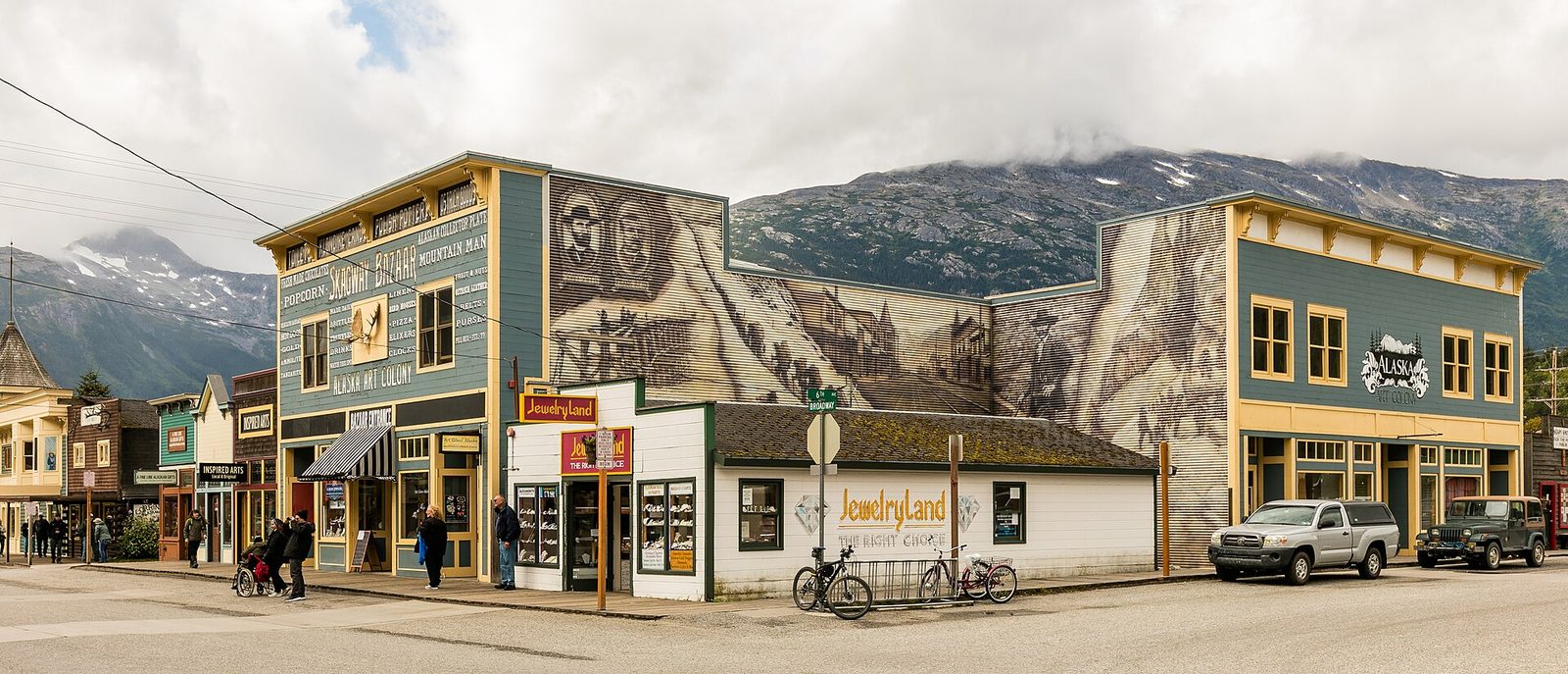Historic small-town main street lined with colourful shopfronts beneath mountains