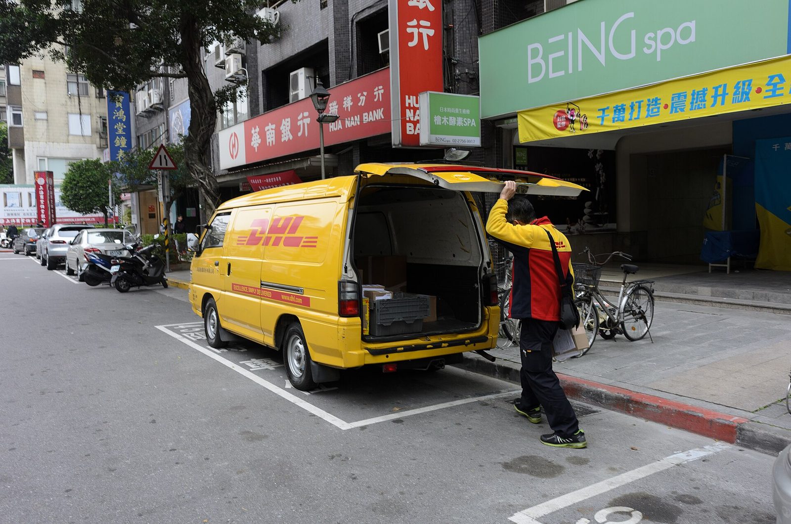 Delivery van parked at the kerb while the driver unloads a parcel