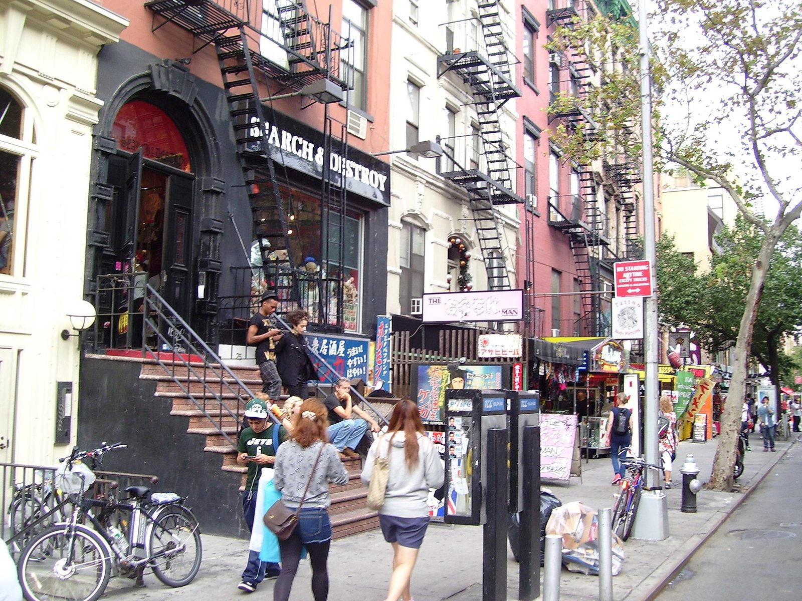 Busy city shopping street with storefront signs, stoops and pedestrians