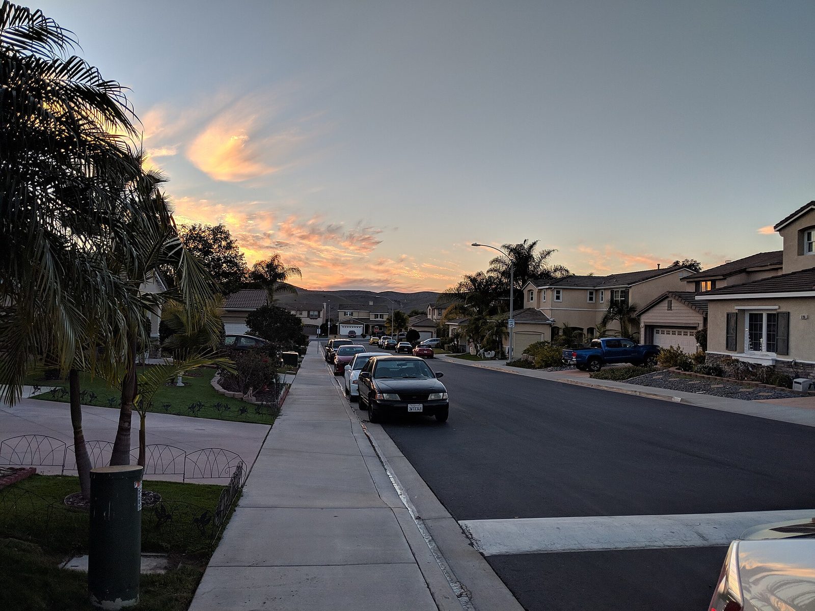 Quiet suburban residential street with sidewalk and houses at sunset
