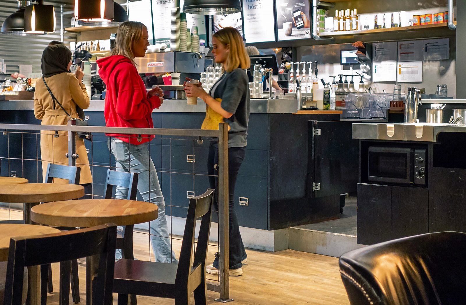 People chatting together at the counter of a busy cafe