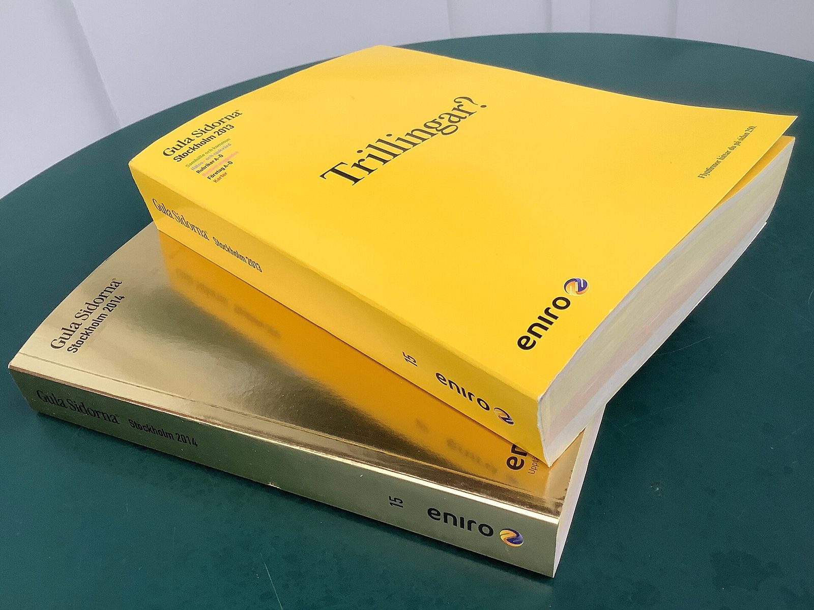 Two thick yellow pages directories stacked on a green table